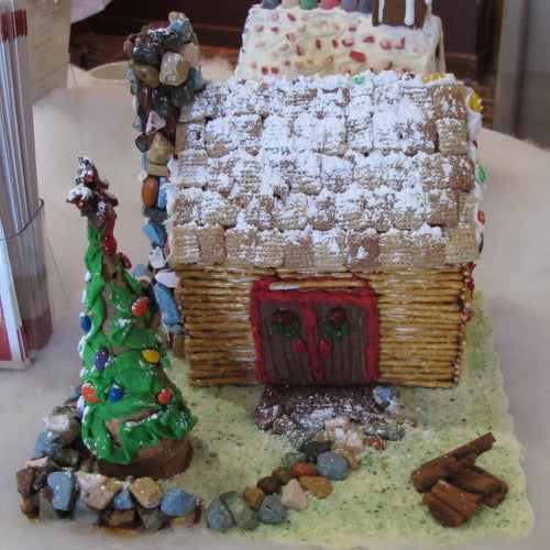 Gingerbread house with a Christmas tree and decorative elements on a white surface
