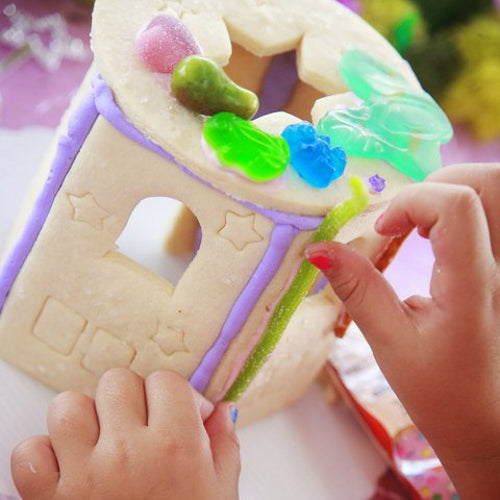 Children's hands playing with a colorful play dough house