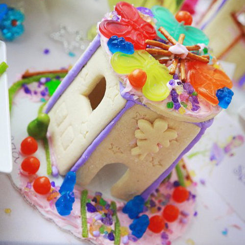 Colorful gingerbread house decorated with candy on a white plate