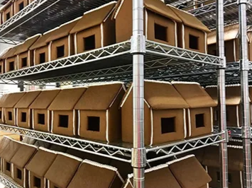 Gingerbread houses on metal shelves in a storage setting