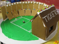 Gingerbread model of a sports stadium with a 'Ticket' stand on a white surface