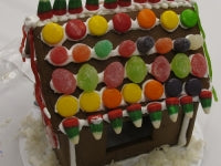 Gingerbread house decorated with colorful candies on a white background