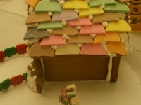 Gingerbread house with colorful roof and candy decorations on a wooden surface.