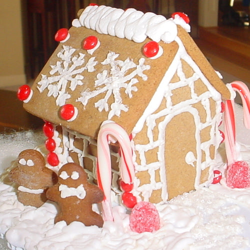 Decorative gingerbread house with gingerbread men and candy decorations on a white surface.