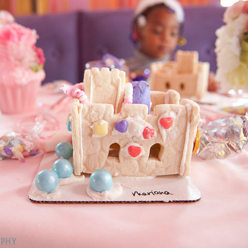 Gingerbread house with colorful candies on a table with a child in the background