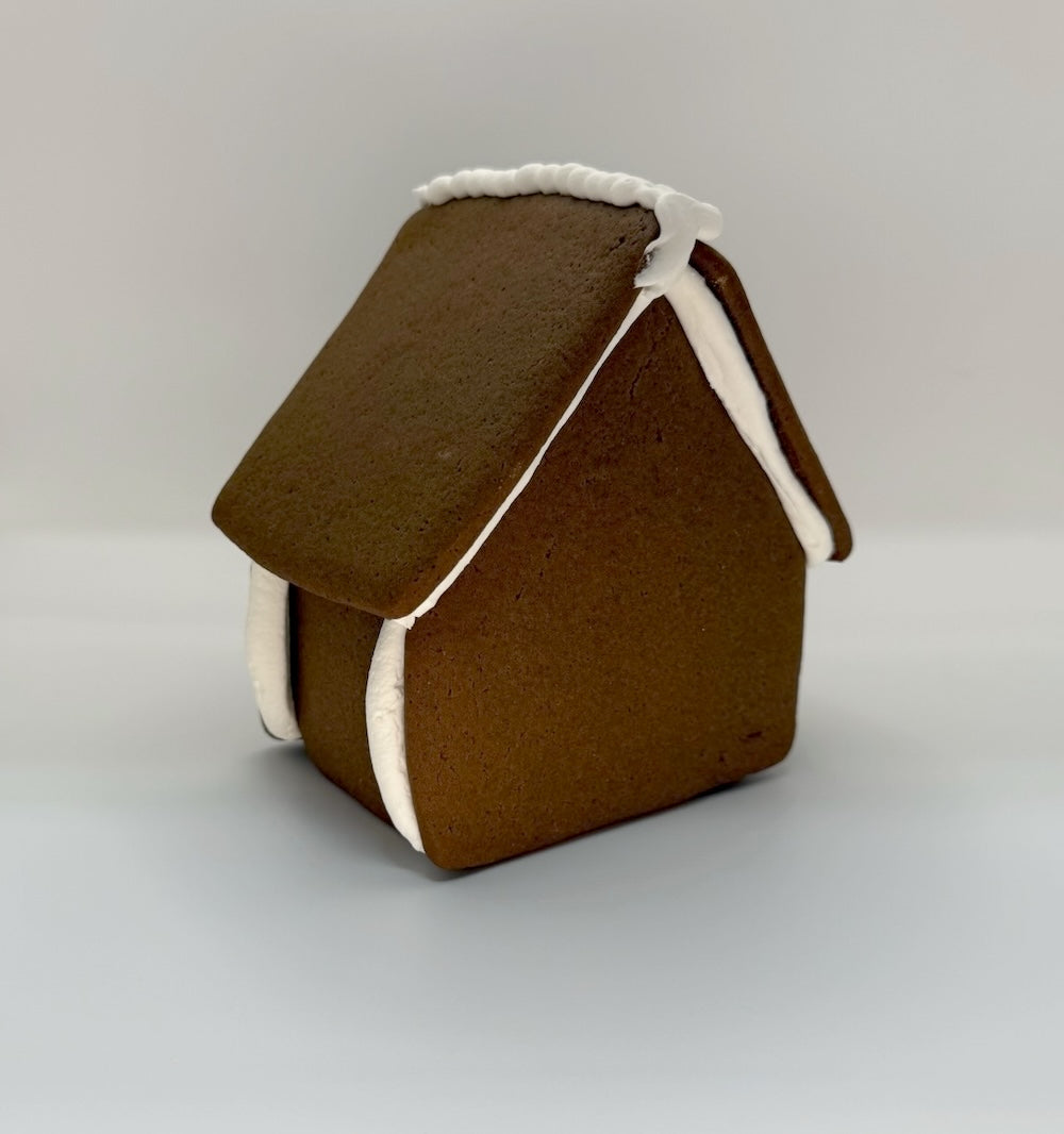 Brown gingerbread house with white trim on a light gray background
