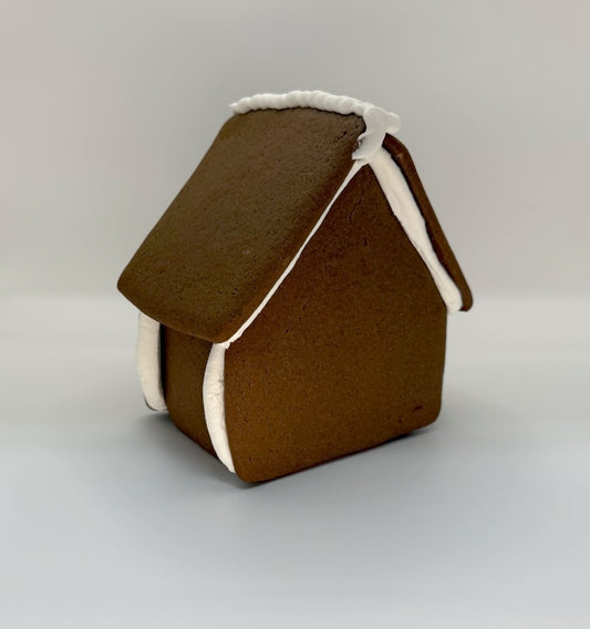 Brown gingerbread house with white trim on a light gray background