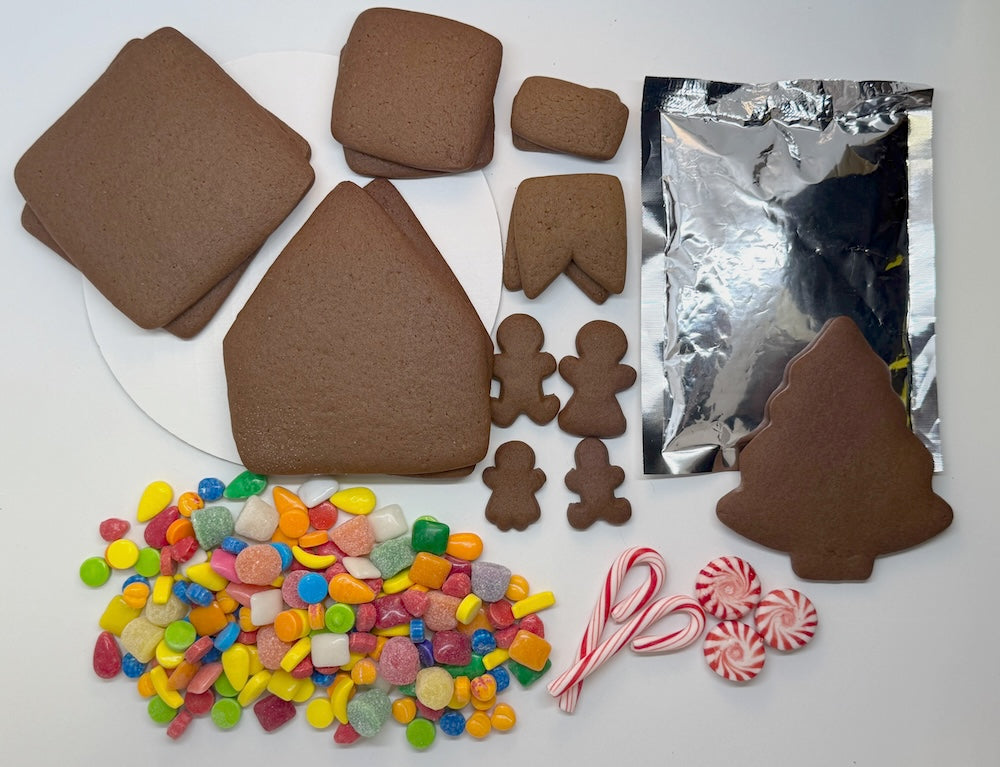Gingerbread house kit with gingerbread people, candy canes, and colorful candies on a white background