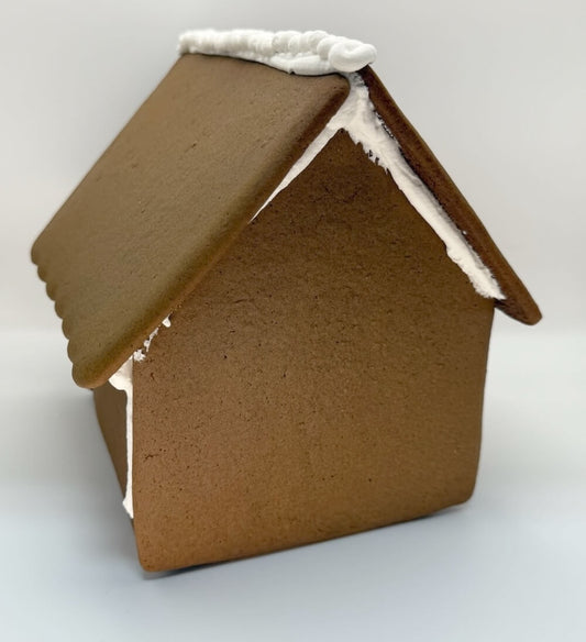 Gingerbread house with a brown roof and white icing on a white background