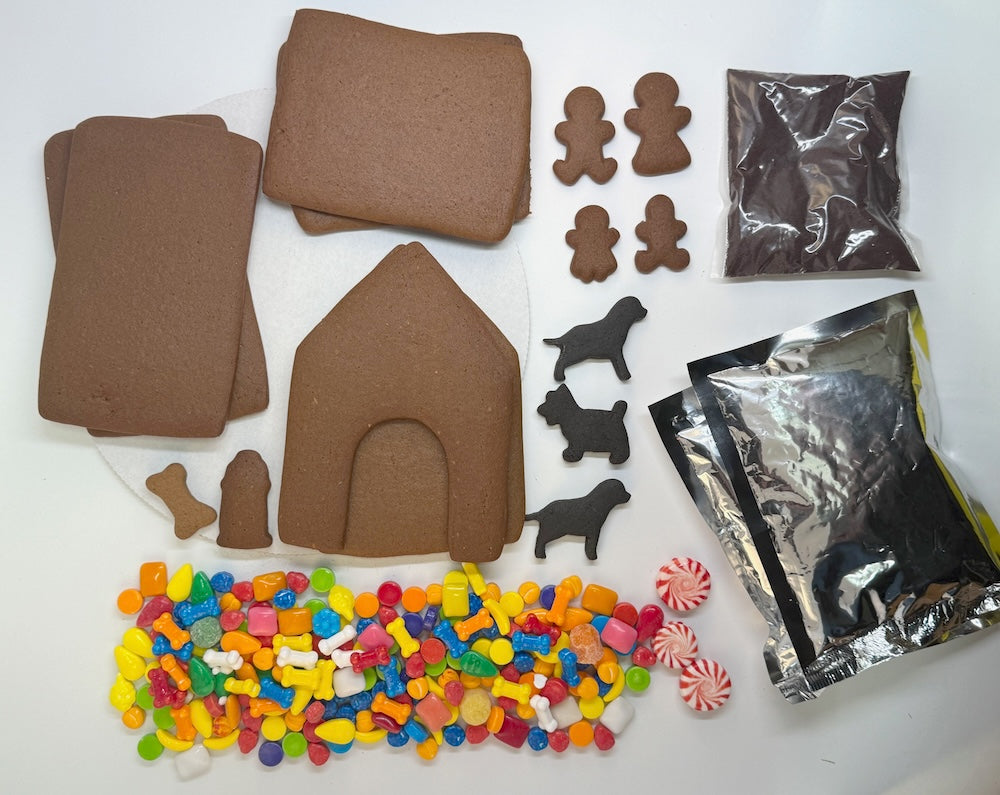 Gingerbread house kit with brown cookie sheets, gingerbread people, dog figures, and candy on a white background.