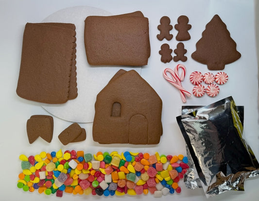 Gingerbread house kit with cookies, candy, and supplies on a white surface